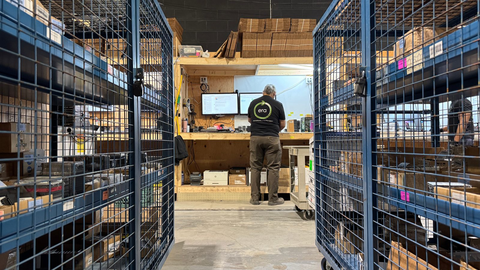 ERA technician at a workstation between locked equipment cages — secure chain-of-custody intake
